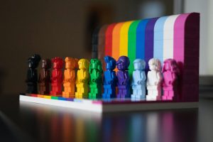 Set of Lego people, each a different colour to represent the Progress Pride Flag