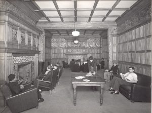 Black and white photo of Mere Hall Hostel for Indian Seamen in Liverpool, showing sailors reading and chatting by the fire