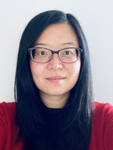 Headshot of Xiaochun Zhang - she is looking directly at the camera and is wearing a black and red top and glasses.