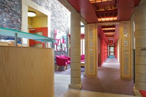 The entrance lobby and hallway in the Faculty of Arts, with pillars, brick wall and red furniture